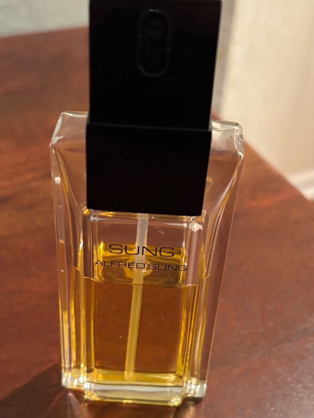 ALFRED SUNG Clear Glass Bottle with Amber Liquid and Black Cap